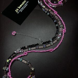 Vue d'ensemble d'un baya (chaîne de taille) composé de plusieurs rangs de perles roses, noires et transparentes irisées.