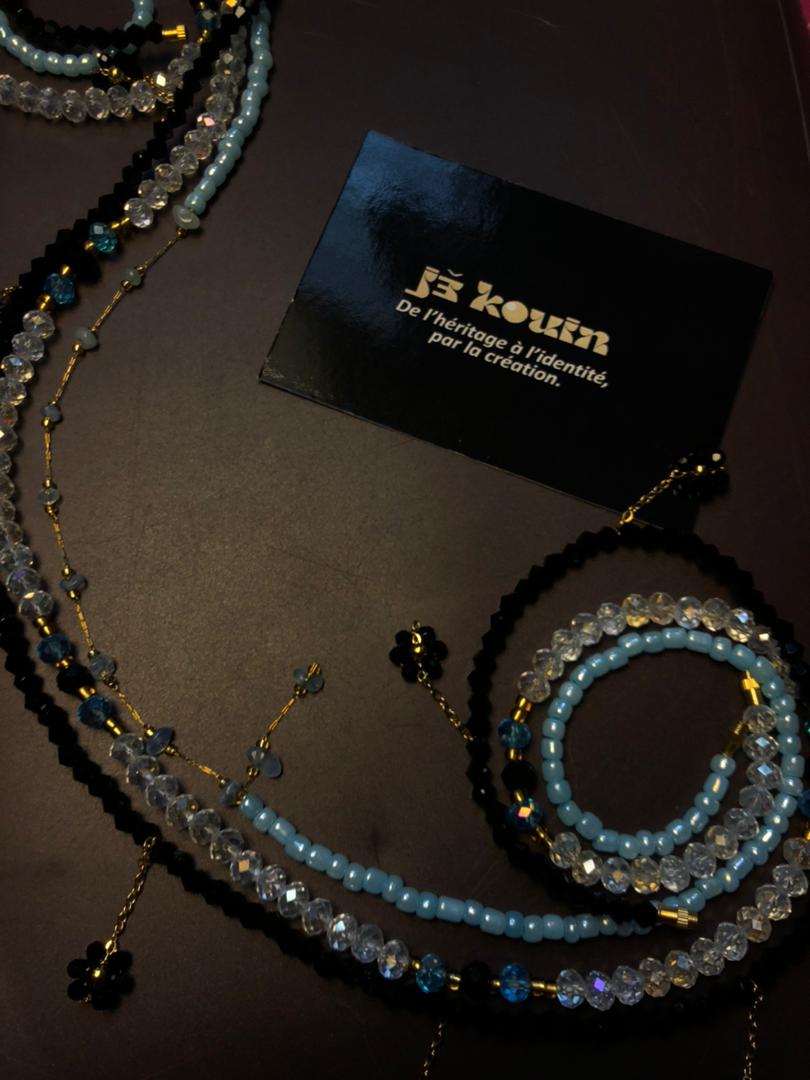 Vue d'ensemble de bayas noirs et bleus serpentant sur un fond sombre, disposés de part et d'autre de la carte de visite jǯ kouin.