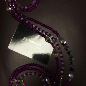 Chaîne de taille baya en cristal violet intense avec pendentifs gouttes en verre translucide ondulant autour d'une carte de visite jekouin.