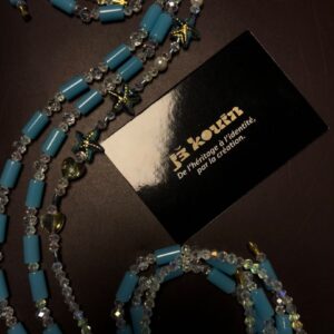Vue cadrée du baya turquoise "Bassins de corail" révélant des perles en forme d'étoiles de mer et de cœurs en cristal transparent sur fond sombre.
