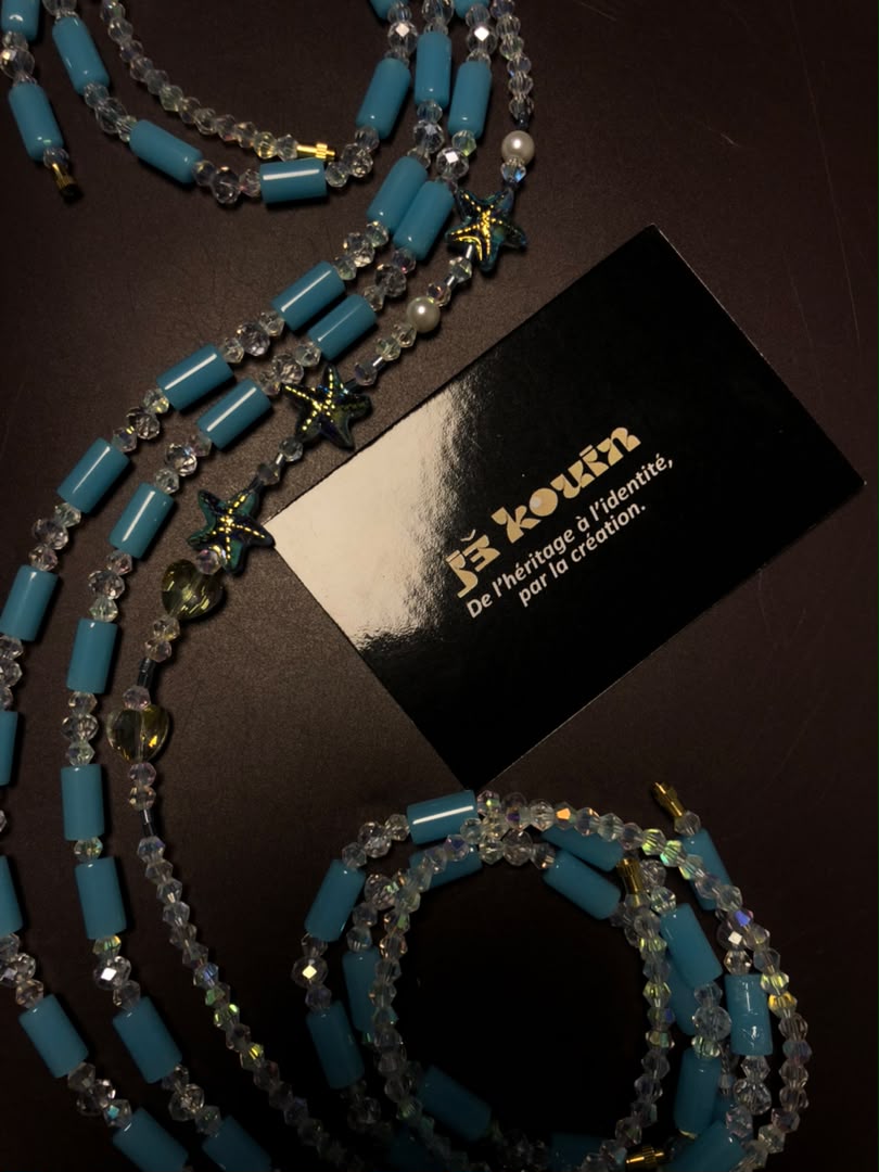 Vue cadrée du baya turquoise "Bassins de corail" révélant des perles en forme d'étoiles de mer et de cœurs en cristal transparent sur fond sombre.