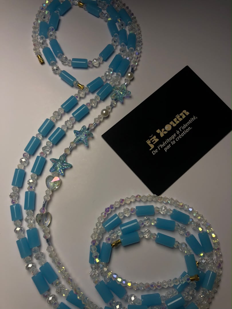 Bijou de corps baya turquoise enroulé en spirale sur fond blanc/gris clair avec carte de visite noire jekouin.